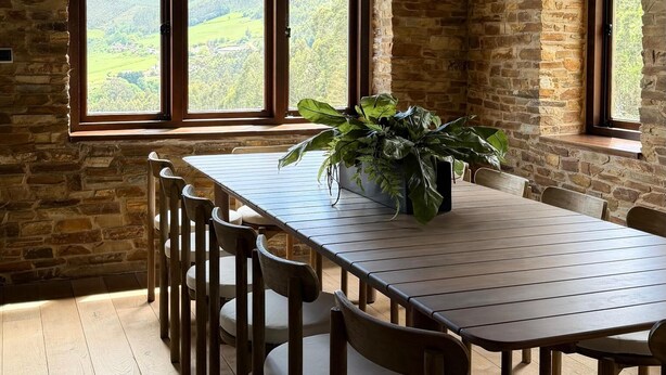 A rustic dining room with a long wooden table, chairs, and a hanging light fixture. - Luxury house in front of the valley, 20 minutes from Las Catedrales beach. (San Tirso de Abres)