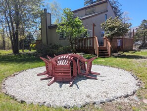 A red outdoor seating area with a gravel circle, a wooden deck, and a house in the background. - Quiet Poconos Chalet with Loft Lounge (ALBRIGHTSVLLE)