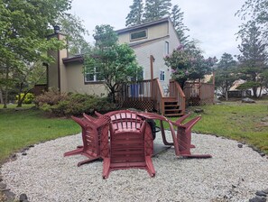 Une maison avec une terrasse, un escalier et un espace recouvert de gravier, agrémenté de chaises rouges.