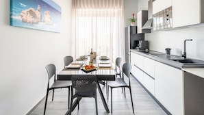 Une cuisine moderne avec un coin repas, un tableau au mur et une fenêtre ornée de rideaux légers.
