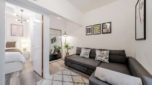 Una sala de estar moderna con un sofá gris, un tapete blanco y obras de arte enmarcadas en la pared.