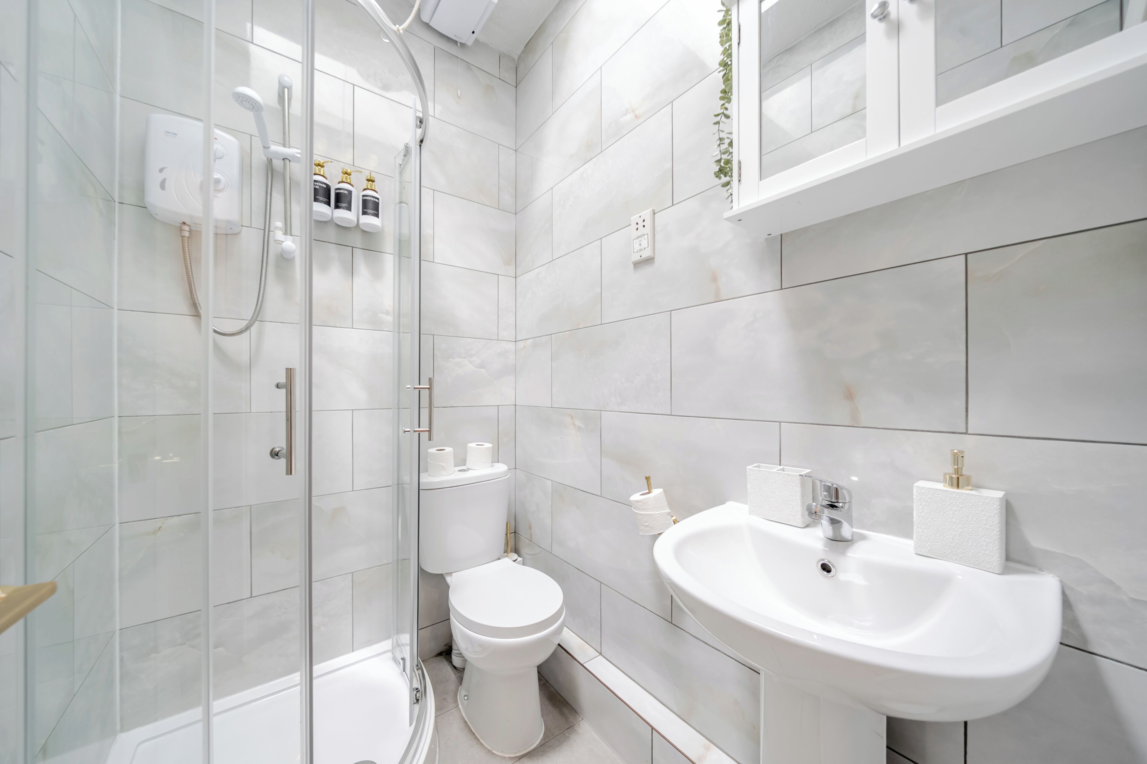 A modern bathroom with a glass-enclosed shower, a toilet, and a sink with a mirror above it.