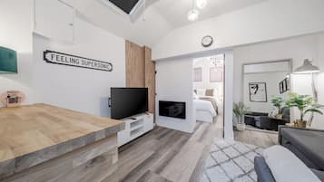 A modern living room with a wooden dining table, a flat-screen TV, and a sofa.