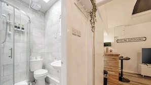 Un baño moderno con cabina de ducha de vidrio, inodoro y lavamanos.