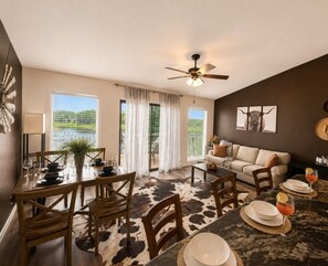 A dining area with a table set for four, a sofa, and a ceiling fan. - Adventure West-Lakefront 1BD/1BA/Indoor/Outdoor Pool/Hottub/Grill/Pickleball/Pet Friendly-4PP (Village of Four Seasons)