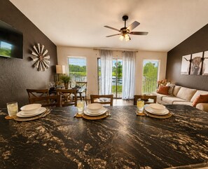 A dining area with a large marble table, chairs, and a ceiling fan. - Adventure West-Lakefront 1BD/1BA/Indoor/Outdoor Pool/Hottub/Grill/Pickleball/Pet Friendly-4PP (Village of Four Seasons)