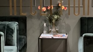 A reception area with a dark green sofa, a small table with a vase of flowers, and a wall with the word 'RECEPTION' in gold letters.