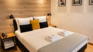 Une chambre d’hôtel moderne avec un grand lit, des tables de chevet, un téléphone et une lampe fixée au mur.