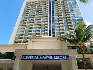 Ein hohes Hotelgebäude mit der Aufschrift 'Imperial Hawaii Resort' am Fuße.