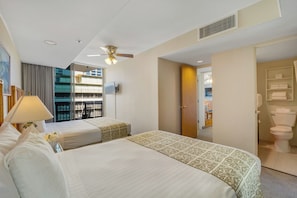 Ein Hotelzimmer mit zwei Betten, einem Deckenventilator, einem Fernseher und Blick auf den Außenbalkon.