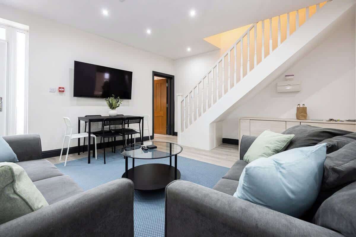 A modern living room with a sofa, a coffee table, and a TV mounted on the wall.