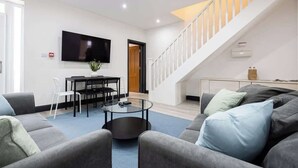 Un salon moderne avec un canapé, une table basse et un téléviseur fixé au mur.