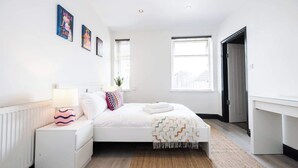 Une chambre moderne avec un lit, des tables de chevet, un bureau et une fenêtre.