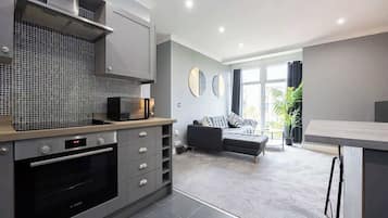 Una cocina moderna con horno Bosch, armarios grises y salpicadero de azulejos.
