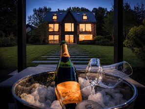A bottle of champagne in an ice bucket with glasses, set outdoors with a house in the background. - Exclusive Cheshire Mansion | Private Grounds (Cheshire East)