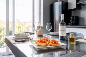Une table à manger avec une assiette de bruschettas, une bouteille de vin Negrami Pugliano et une bouteille d’huile d’olive.