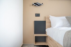 A bedroom with a bed, a nightstand, a wall-mounted charging station, and a power outlet. - 'Piazza Pertini - Room Ambra' with Balcony, Wi-Fi and Air Conditioning (Melendugno)