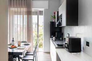 A modern kitchen with a dining area, a coffee machine, and a view of the outdoors. - 'Piazza Pertini - Room Ambra' with Balcony, Wi-Fi and Air Conditioning (Melendugno)