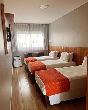 A hotel room with three beds, a wooden headboard, a small desk, and a window with sheer curtains. - Califórnia Suítes (Belo Horizonte)