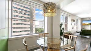 Un espace repas moderne avec une table en verre, des chaises en osier et un luminaire suspendu aux motifs géométriques.