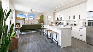 Une cuisine moderne avec des meubles blancs, un îlot central et des tabourets de bar.
