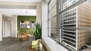 Un intérieur moderne comprenant un coin repas, une grande fenêtre donnant sur un parking et un mur d’accent de couleur verte.