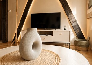 Ein modernes Wohnzimmer mit einer Steinvase auf einer gewebten Unterlage, einem weißen Schrank und einem Flachbildfernseher.