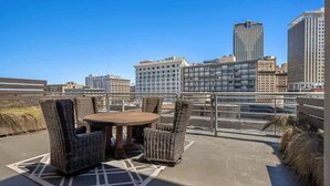A rooftop terrace with wicker furniture and a city view. - Spacious Luxury: 4BR Condo Moments from FQ (New Orleans)