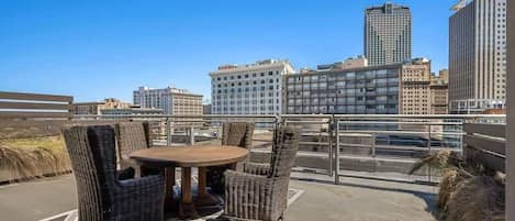 A rooftop terrace with wicker furniture and a city view.