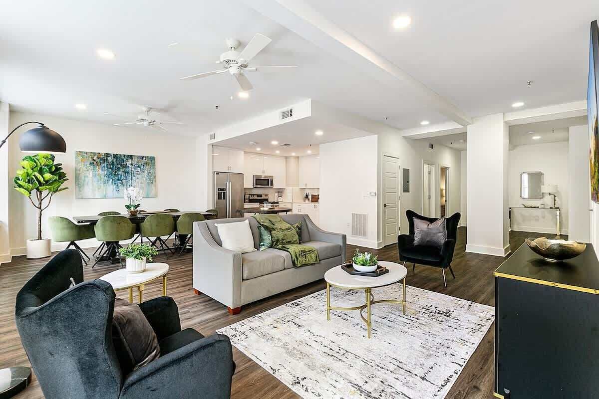 A modern living room with a sofa, chairs, a coffee table, and a dining area with a table and chairs.