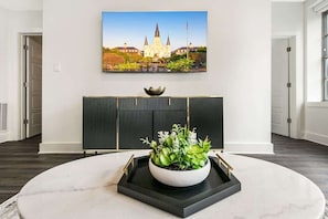 Ein modernes Interieur mit einem Marmortisch, einem Blumentopf, einem gerahmten Bild und einer schwarzen Platte.