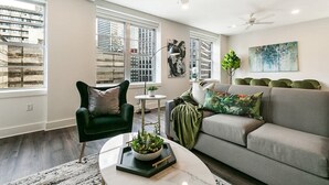 A modern living room with a sofa, armchair, and coffee table, large windows, and ceiling fans. - Spacious Luxury: 4BR Condo Moments from FQ (New Orleans)