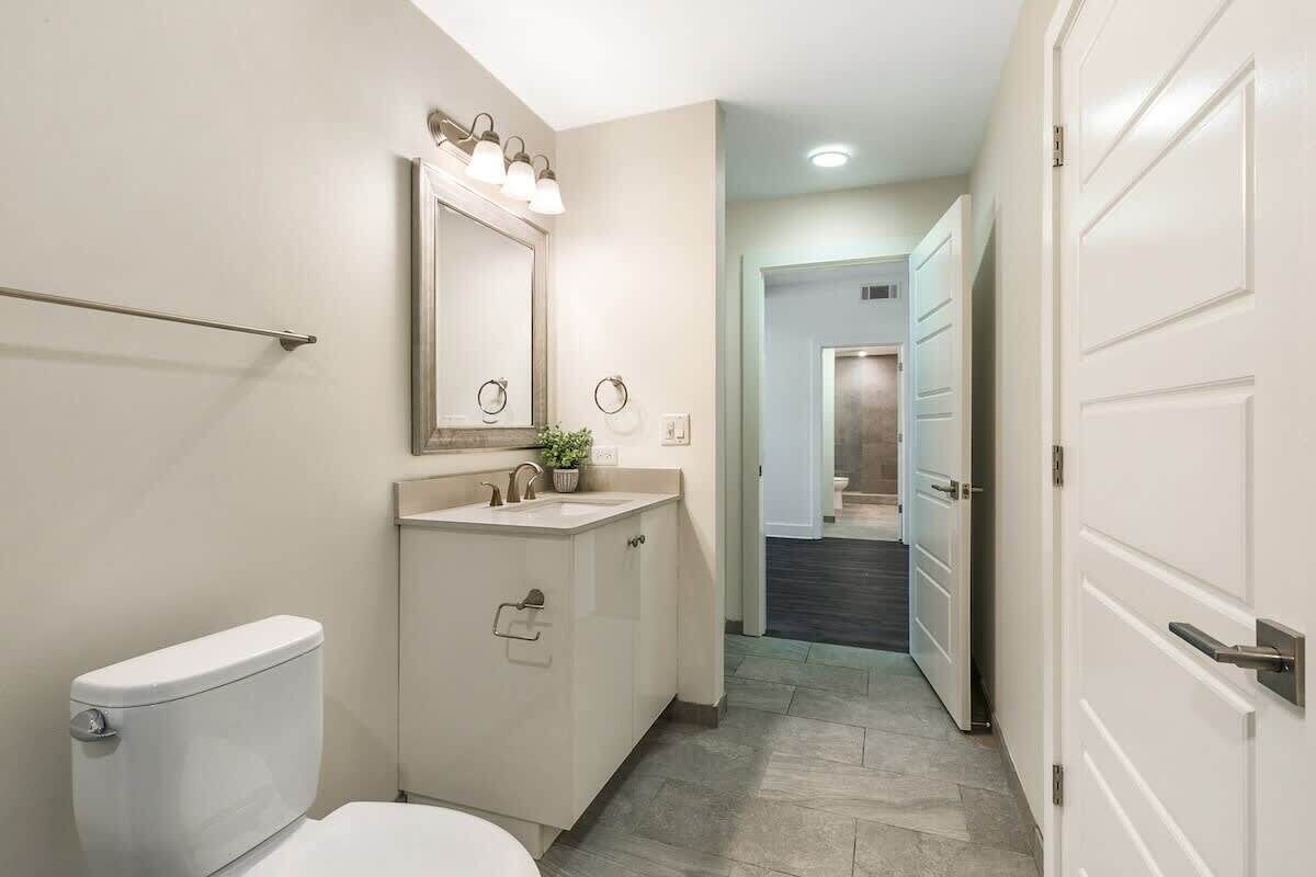 Un baño con inodoro, lavabo, espejo y toallero.