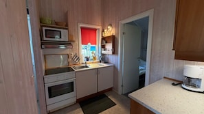 Eine kleine Küche mit Mikrowelle, Backofen, Spüle und Kaffeemaschine.