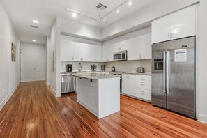 Una cocina moderna con armarios blancos, electrodomésticos de acero inoxidable y suelo de madera.