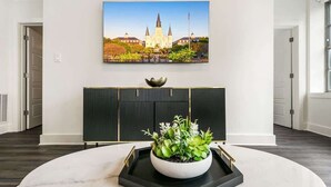 A modern interior with a marble table, a potted plant, a framed picture, and a black panel. - Captivating Condo 5-minute Walk to French Quarter (New Orleans)