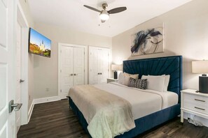 Un dormitorio con cama, ventilador de techo, un cuadro y una puerta.