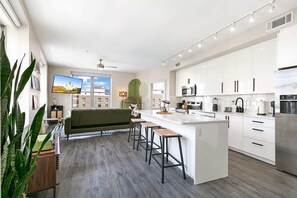 Una cocina moderna con armarios blancos, una isla central y taburetes de bar.