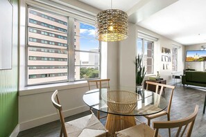 Un comedor moderno con una mesa de vidrio, sillas de mimbre y una lámpara colgante de diseño geométrico.