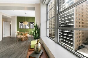 Un interior moderno con zona de comedor, un ventanal con vista a un estacionamiento y una pared de acento verde.