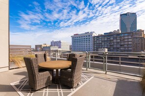 Une terrasse sur le toit, meublée de mobilier en osier, offrant une vue sur les gratte-ciel de la ville et un ciel dégagé.