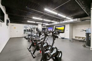 Un gimnasio con bicicletas estáticas, cintas de correr y una pantalla de televisión.