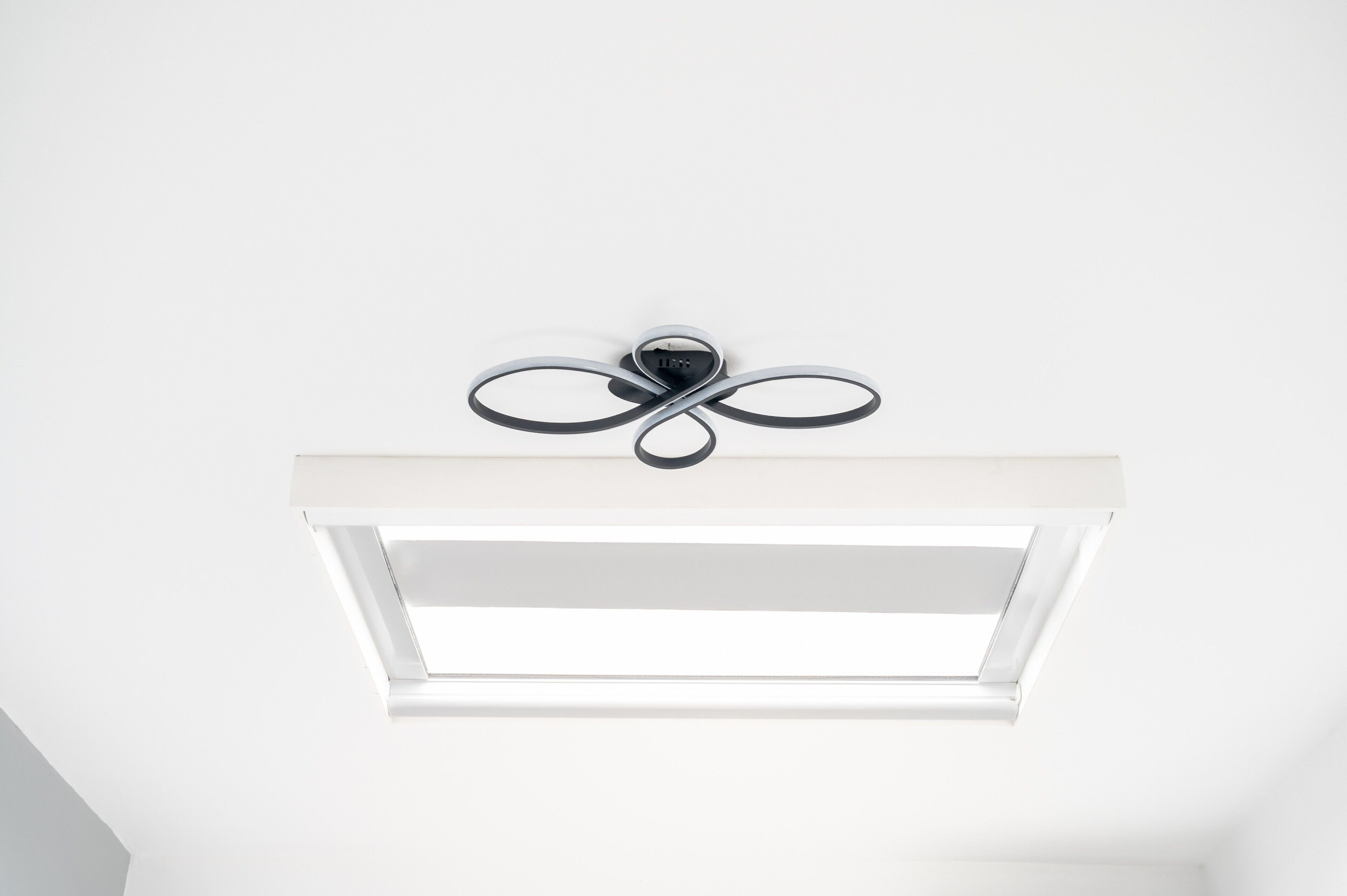 Ein Deckenventilator mit Leuchte und einem rechteckigen Dachfenster.