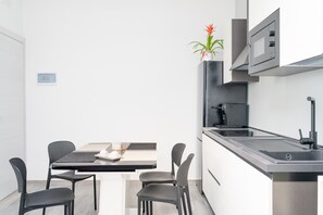 Una cocina moderna con microondas integrado, cafetera y pileta de acero inoxidable.