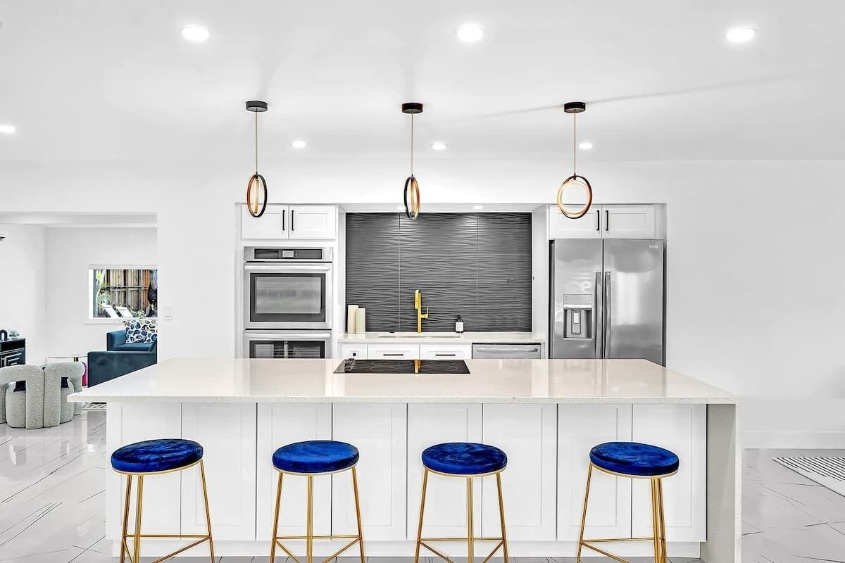 A modern kitchen with a central island, bar stools, and stainless steel appliances.
