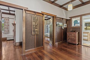 Una habitación con suelo de madera, una puerta corredera con panel decorativo, un armario pequeño y una ventana con vistas.