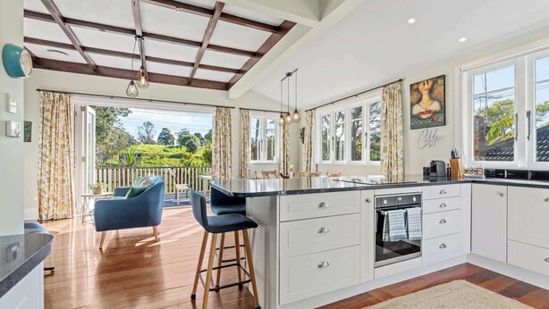 A modern kitchen with a large island, white cabinetry, and a view of the outdoors.