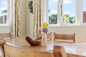 A wooden dining table with a vase of crocheted flowers and a wooden spoon. - Coastal Retreat close to Devonport Beaches (Auckland)
