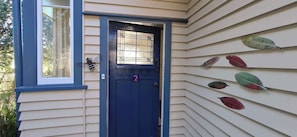 A house with a blue door, a number '2' on the door, and a window with a decorative insect.