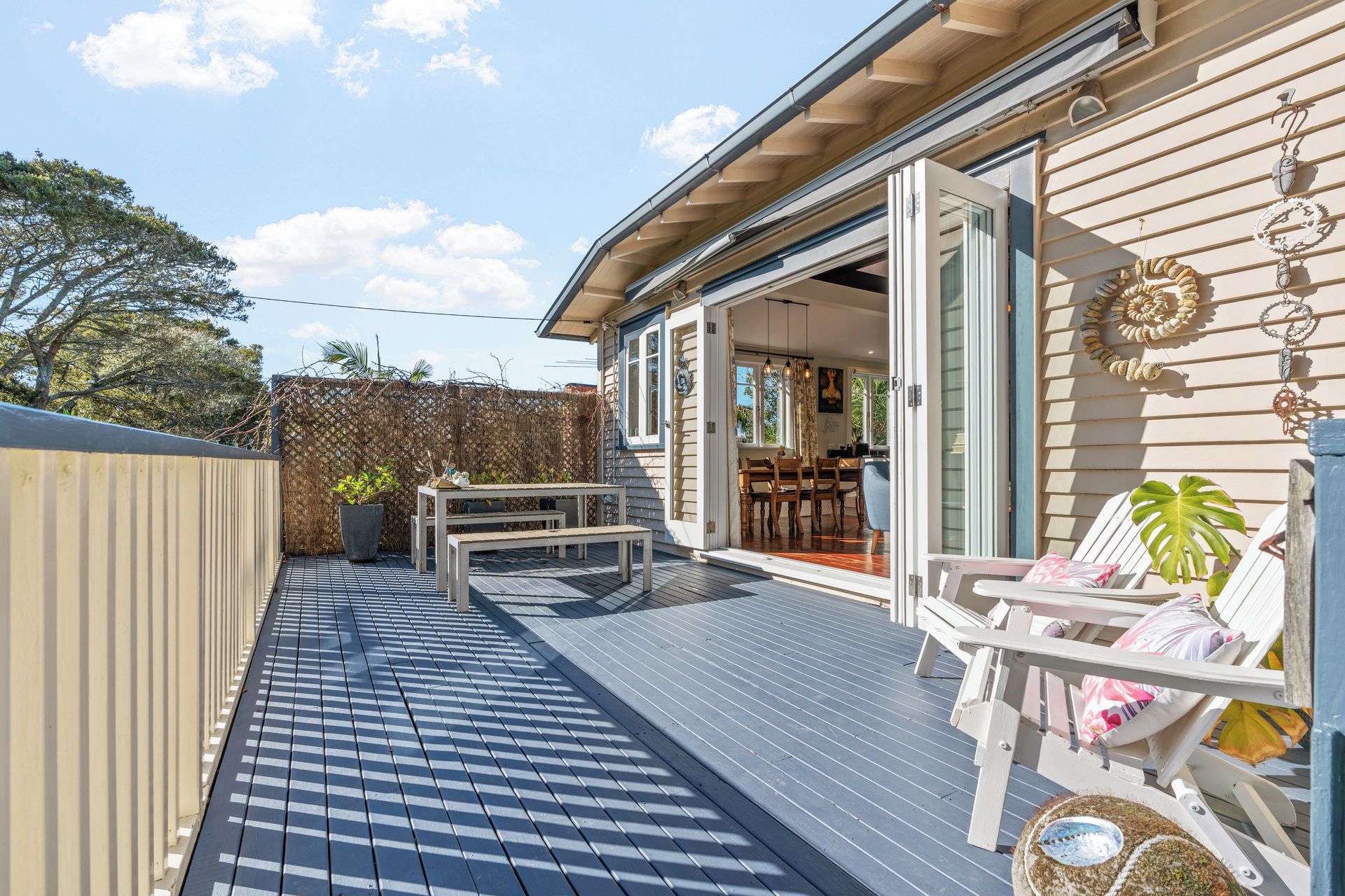 A deck with a dining area, a covered seating area, and a view of the interior.